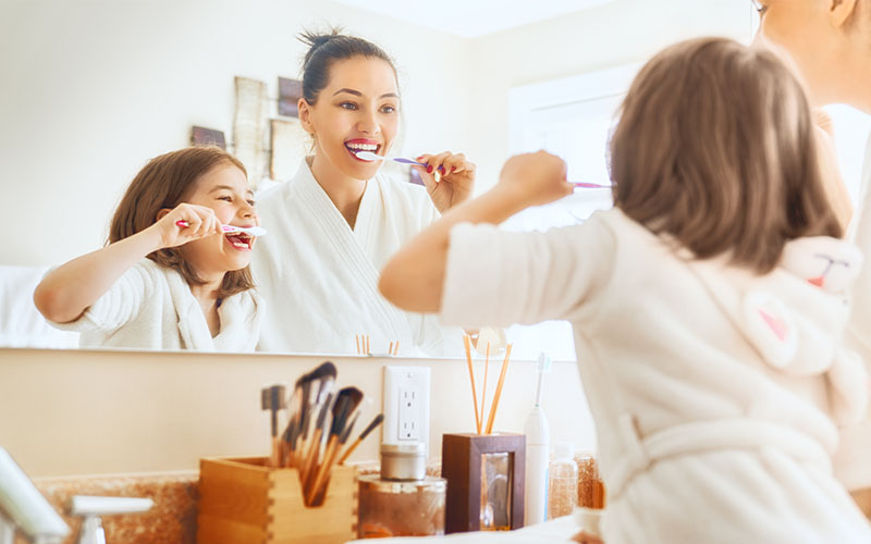 Griesbach Dental - Young patient and her parent brushing their teeth